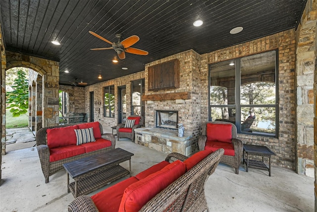 view of patio / terrace with ceiling fan and an outdoor living space with a fireplace