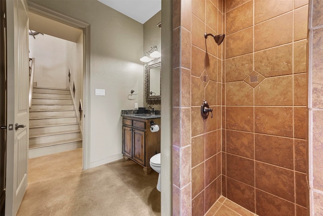 bathroom with vanity, toilet, a tile shower, and concrete floors