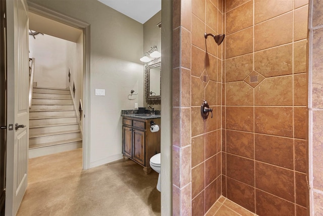 bathroom featuring toilet, finished concrete flooring, vanity, and tiled shower