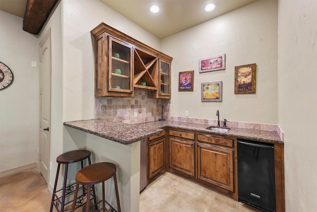 bar featuring decorative backsplash, black dishwasher, dark stone counters, sink, and light colored carpet