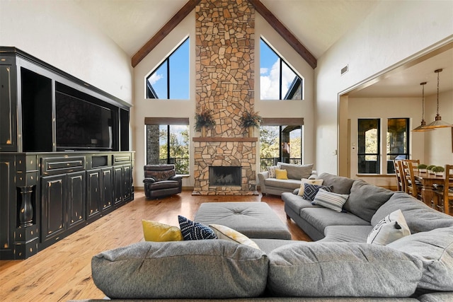 living room featuring a stone fireplace, beamed ceiling, high vaulted ceiling, and wood finished floors