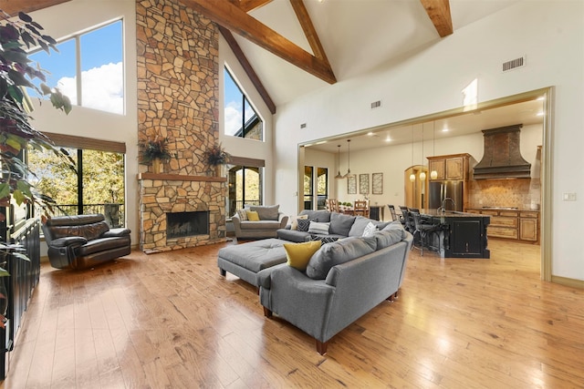 living room with beamed ceiling, light wood-type flooring, high vaulted ceiling, and plenty of natural light