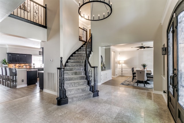 foyer with ceiling fan with notable chandelier and ornamental molding