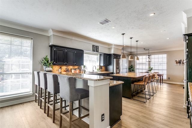 kitchen with a textured ceiling, a center island, decorative light fixtures, and a breakfast bar area