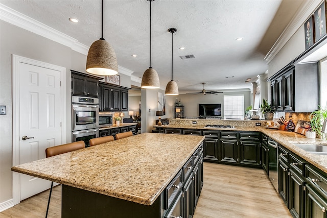 kitchen with ceiling fan, a center island, stainless steel appliances, a kitchen breakfast bar, and decorative light fixtures