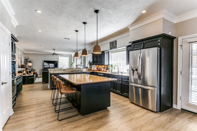 kitchen with a textured ceiling, a center island, hanging light fixtures, and stainless steel refrigerator with ice dispenser