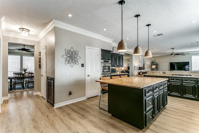 kitchen featuring pendant lighting, a kitchen island, a wealth of natural light, and stainless steel oven