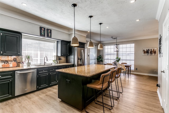 kitchen featuring pendant lighting, a center island, a kitchen breakfast bar, light stone countertops, and appliances with stainless steel finishes