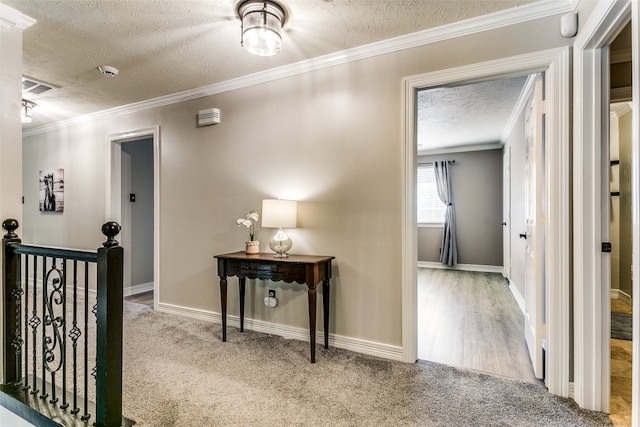 hall with a textured ceiling, light colored carpet, and crown molding