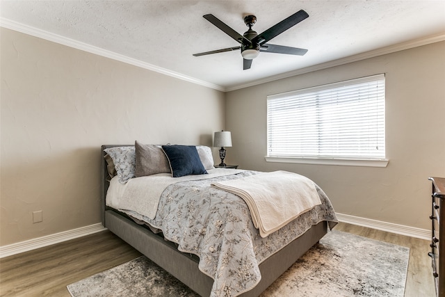 bedroom with hardwood / wood-style floors, ceiling fan, ornamental molding, and a textured ceiling