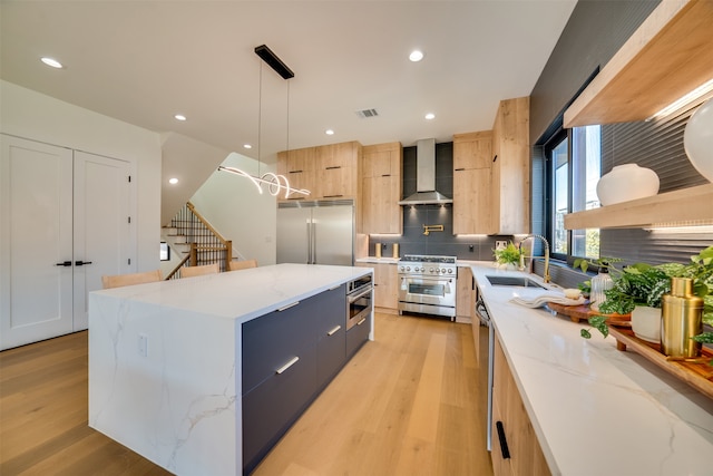 kitchen with wall chimney range hood, a center island, decorative light fixtures, premium appliances, and light stone counters