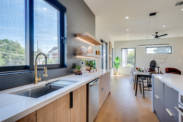 kitchen featuring hanging light fixtures, backsplash, light hardwood / wood-style flooring, dishwasher, and sink