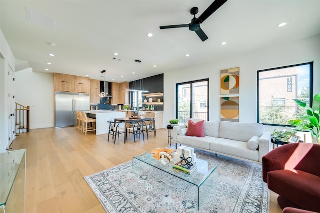 living room with ceiling fan and light hardwood / wood-style flooring