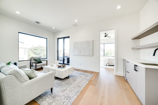 living room featuring sink, ceiling fan, light hardwood / wood-style floors, and plenty of natural light