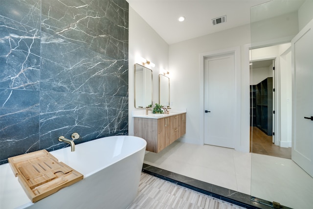 bathroom with vanity, a tub to relax in, tile patterned floors, and tile walls