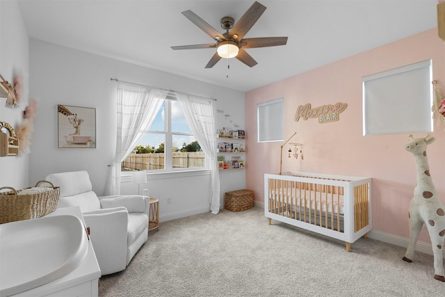 bedroom with baseboards, carpet flooring, a ceiling fan, and a crib