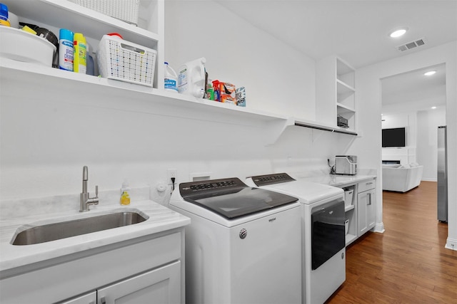 laundry room featuring recessed lighting, wood finished floors, a sink, visible vents, and washing machine and dryer