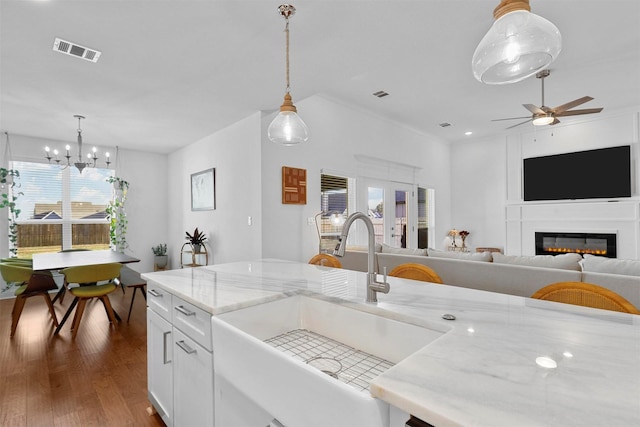 kitchen with dark wood finished floors, a sink, a wealth of natural light, visible vents, and ceiling fan with notable chandelier