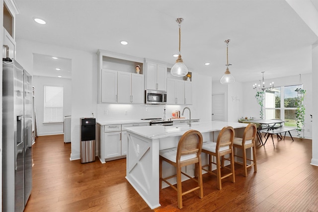 kitchen with an island with sink, stainless steel appliances, white cabinets, and dark hardwood / wood-style flooring