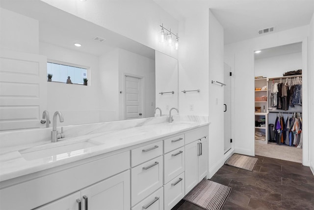 full bath with a sink, a stall shower, double vanity, and visible vents