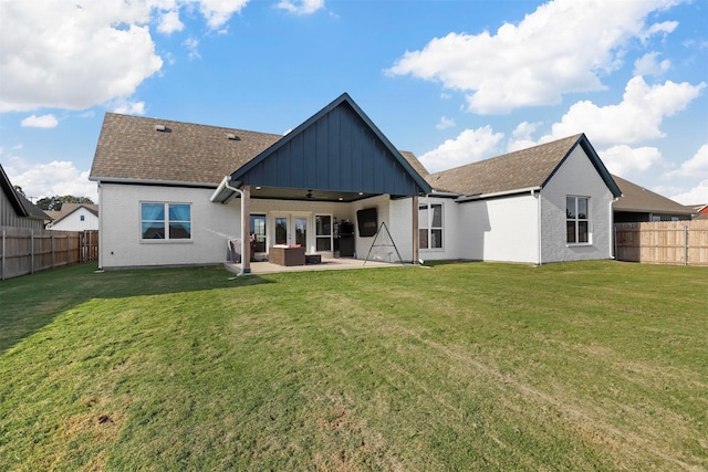 rear view of house featuring a patio, board and batten siding, a fenced backyard, and a yard