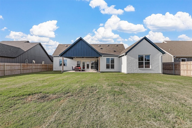 back of property with board and batten siding, a fenced backyard, brick siding, a patio area, and a lawn