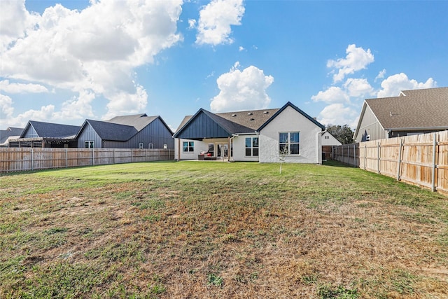 rear view of property featuring a yard and a fenced backyard