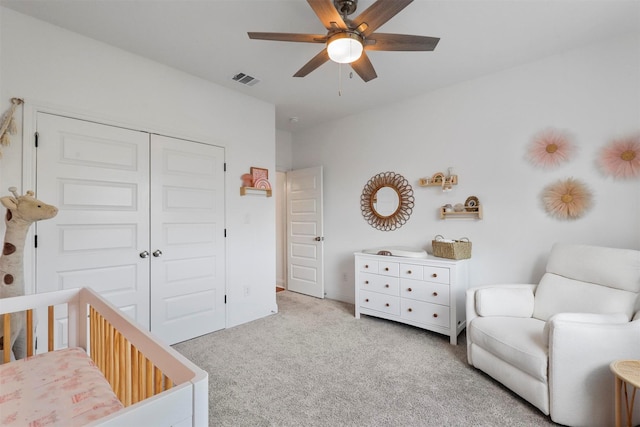 bedroom featuring carpet flooring, visible vents, a nursery area, a closet, and a ceiling fan