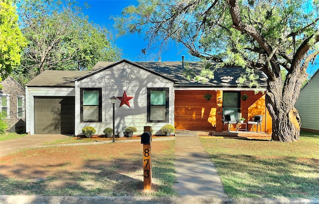 view of front of property with covered porch, a front yard, and a garage