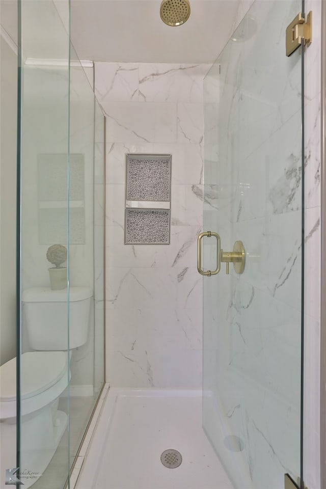 bathroom featuring a shower with shower door and toilet