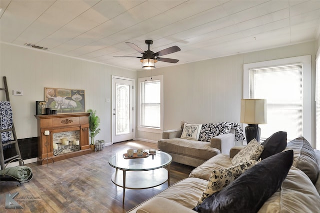 living room with wood walls, hardwood / wood-style flooring, ceiling fan, and a wealth of natural light