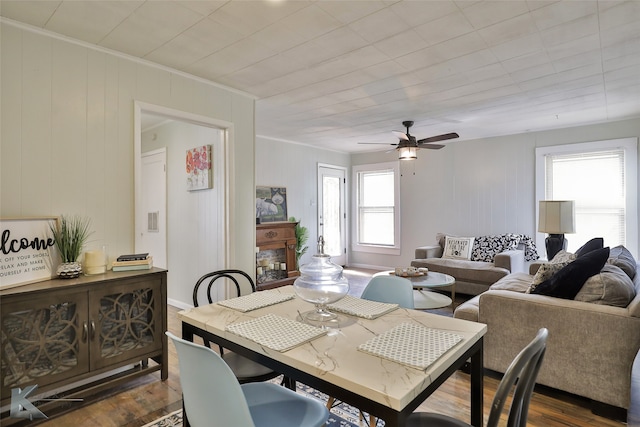 dining area featuring wood walls, dark wood-type flooring, and ceiling fan