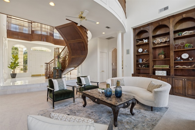 living room featuring ceiling fan, light colored carpet, a high ceiling, and decorative columns