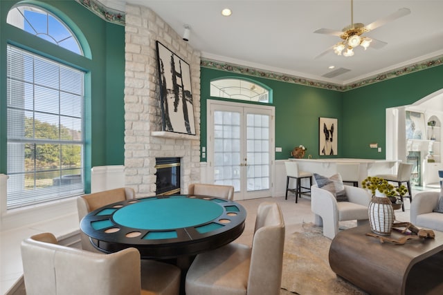 recreation room with french doors, a stone fireplace, plenty of natural light, and ornamental molding