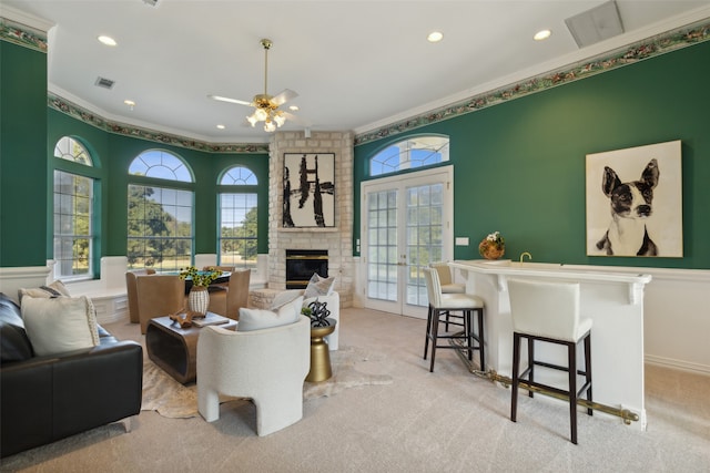 carpeted living room featuring crown molding, french doors, ceiling fan, and a brick fireplace