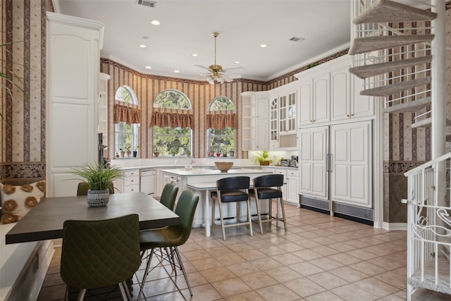 kitchen with ceiling fan, a center island, white cabinets, and ornamental molding