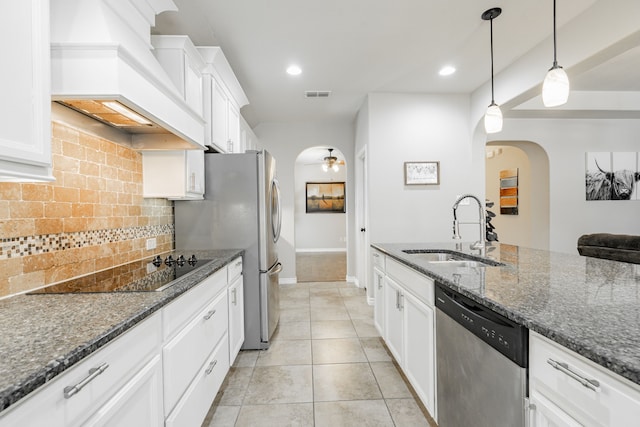 kitchen featuring sink, hanging light fixtures, stainless steel appliances, white cabinets, and dark stone countertops