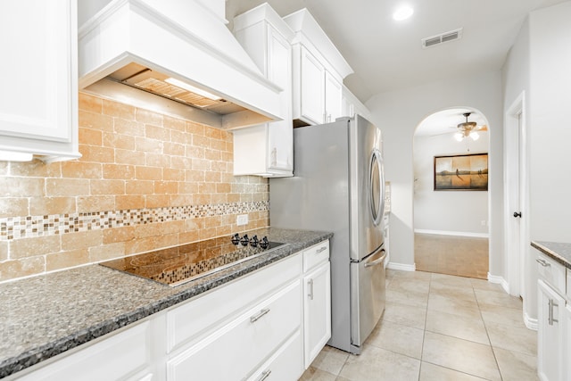 kitchen featuring black electric stovetop, premium range hood, white cabinetry, and dark stone counters