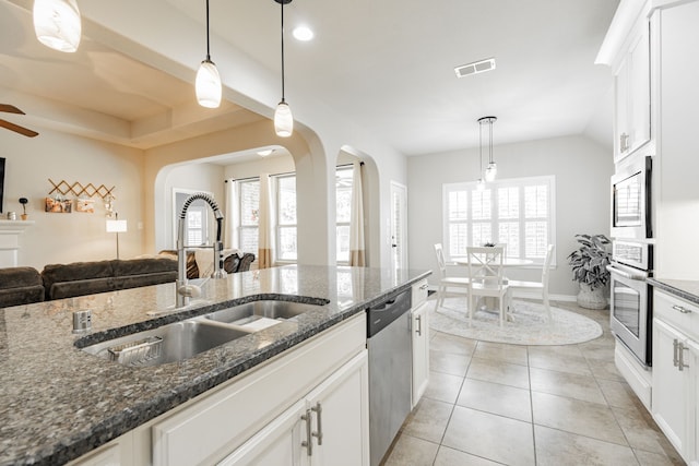 kitchen with decorative light fixtures, stainless steel appliances, sink, and dark stone counters