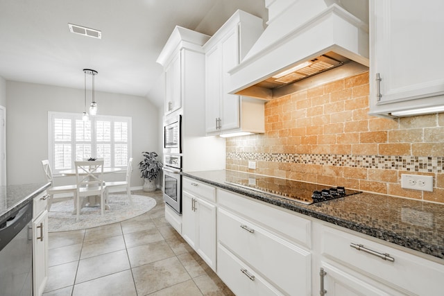 kitchen with appliances with stainless steel finishes, dark stone countertops, white cabinets, and custom range hood