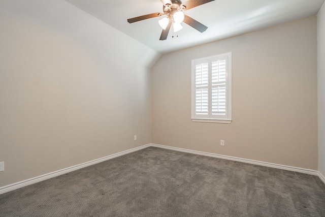 empty room featuring vaulted ceiling, dark colored carpet, and ceiling fan