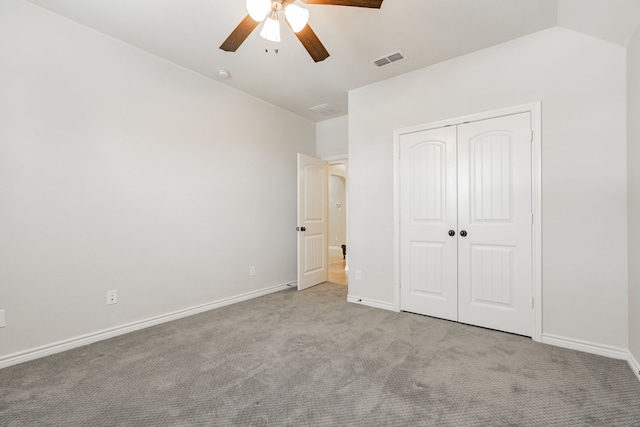 unfurnished bedroom featuring a closet, ceiling fan, light carpet, and lofted ceiling