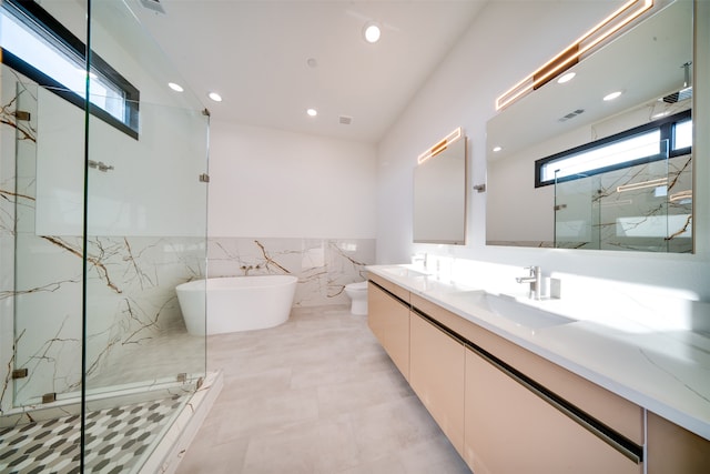 full bathroom with tile walls, vanity, separate shower and tub, and toilet