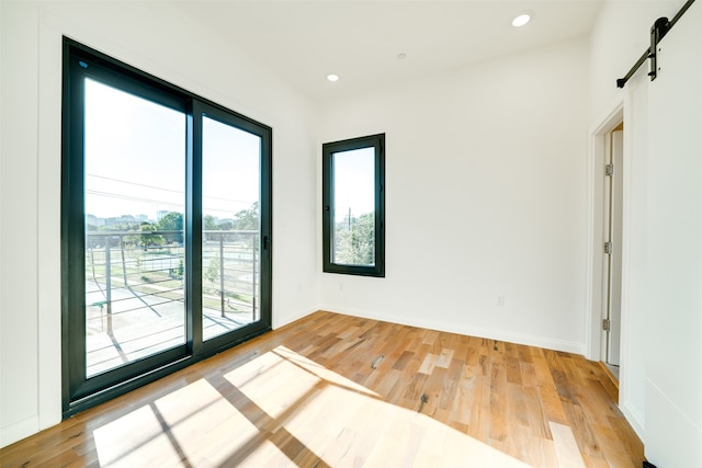 empty room with light hardwood / wood-style floors and a barn door