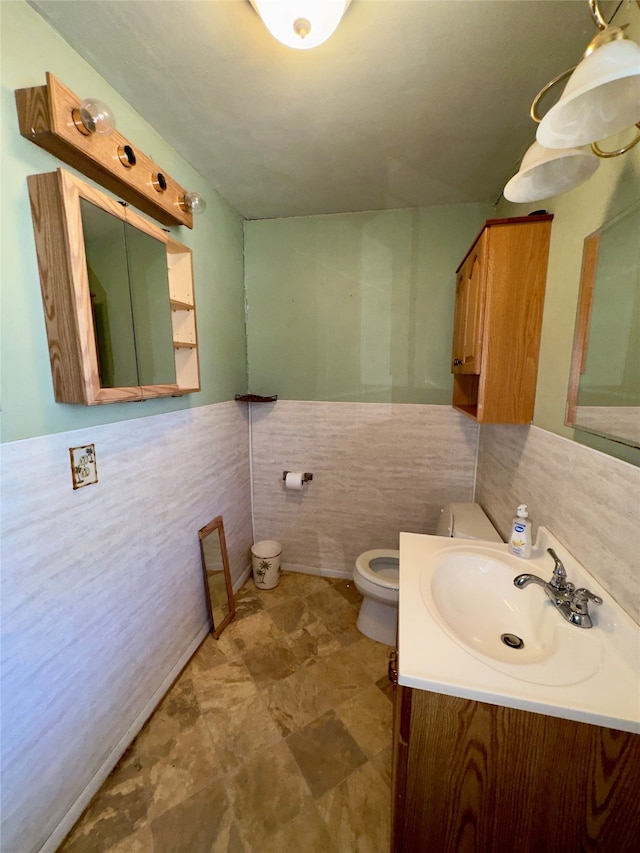 bathroom featuring vanity, tile walls, and toilet