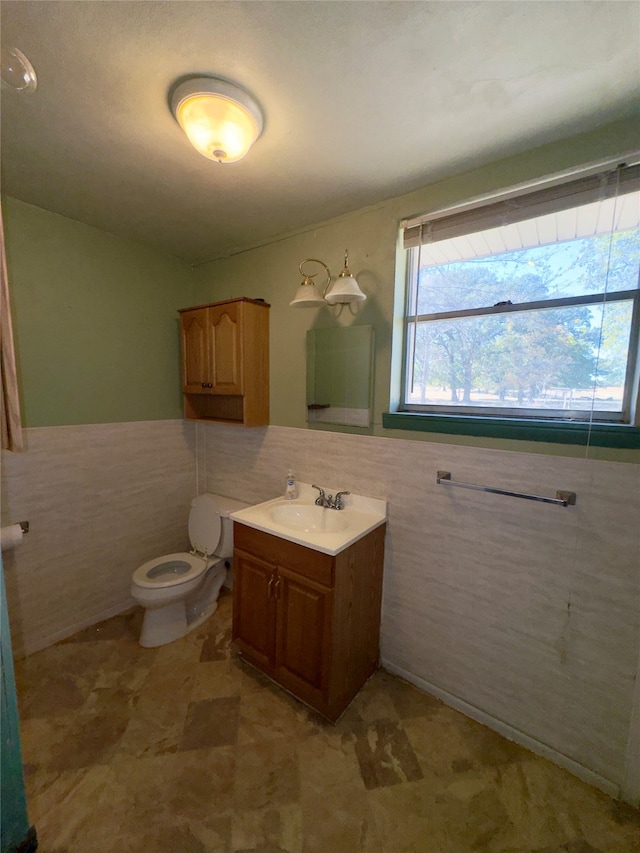 bathroom featuring toilet, vanity, and tile walls