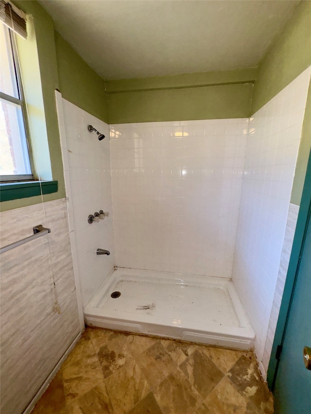 bathroom with a tile shower and tile walls