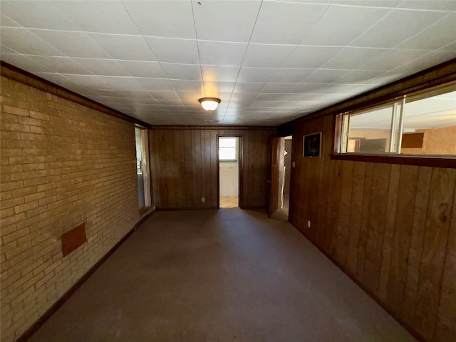 spare room with concrete floors, wooden walls, and brick wall