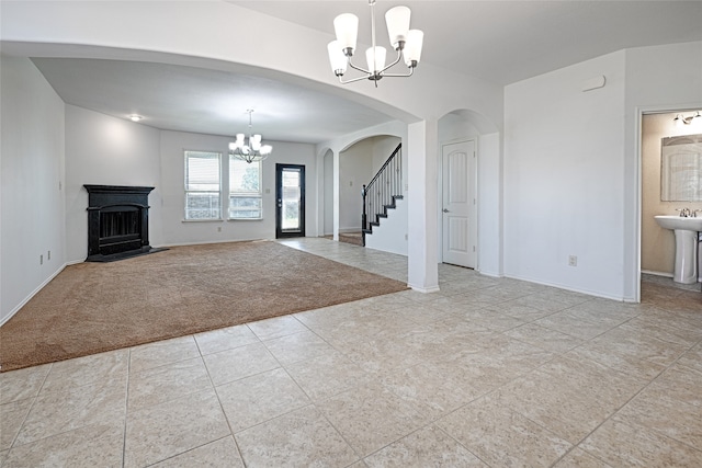 unfurnished living room with light carpet, sink, and a chandelier