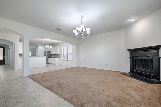 unfurnished living room with an inviting chandelier and light colored carpet